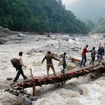 救援者在北阿坎德邦協助人們度過洪水氾濫的河流。（節錄自路透社新聞照）