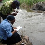 潘加尼盆地水資源局官員Arafa Maggidi（綠色上衣）和Lillian Mkongo在潘加尼河支流取水樣本測量含鹽量。（照片：Kizito Makoye/IPS提供。）