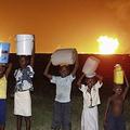 奈及利亞孩童提著水在火炬氣不遠處。圖為Harcourt 港口附近殼牌石油開發公司的Obigbo油田。Peter Roderick 攝；圖片來源﹕ELAW