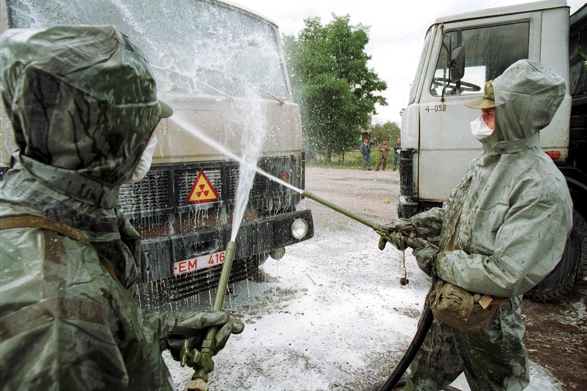 白俄羅斯士兵穿著防護服，在距離車諾比核電廠約50公里、白俄羅斯-烏克蘭邊境附近，為一輛卡車進行除污，清洗車上的放射性塵埃。照片攝於2000年9月21日。圖片來源：EPA/Maxim_Malinovsky（本圖非cc授權／限本文使用）