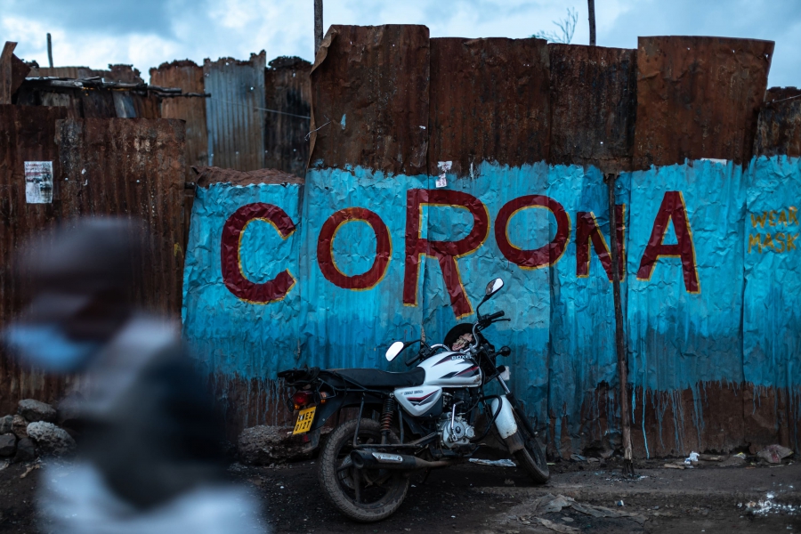 Kibera社區的牆壁上，繪有壁畫「Corona，戴上口罩」。宵禁前仍熱鬧非凡。在這樣的非正式住區，成千上萬的人比鄰而居，許多人擔心維持社交距離和自主隔離是不可能的任務。（2020年4月）攝影： Nichole Sobecki / VII for National Geographic