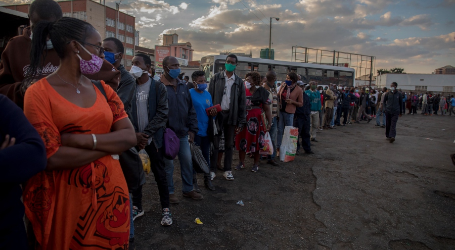 下班的人們，戴著口罩排隊準備搭乘大眾運輸工具回家。（辛巴威，哈拉雷，市集廣場巴士總站，2020年5月）。攝影： Cynthia Matonhodze