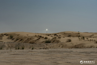 筆直的道路往沙漠的深處前進，遠方一座太陽能公園的聚光塔頂端白光環繞，在大白天中依舊耀眼。